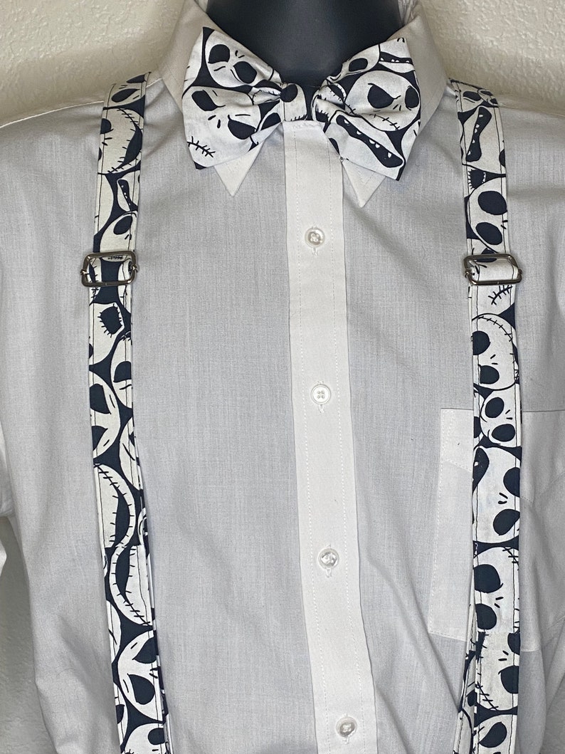 May include: White button-down shirt with black and white suspenders and a black and white bow tie featuring a repeated pattern of Jack Skellington's face from the Nightmare Before Christmas.