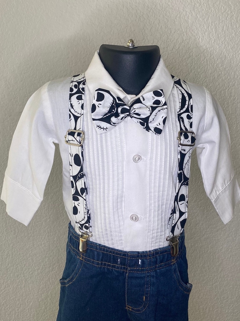 May include: A white button-down shirt with a black and white bow tie and suspenders. The bow tie and suspenders feature a pattern of Jack Skellington's face from the movie The Nightmare Before Christmas.