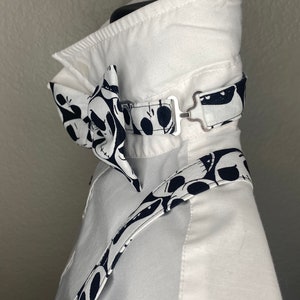 May include: White dress shirt with a black and white bow tie and matching suspenders. The bow tie and suspenders feature a pattern of cartoon skulls.
