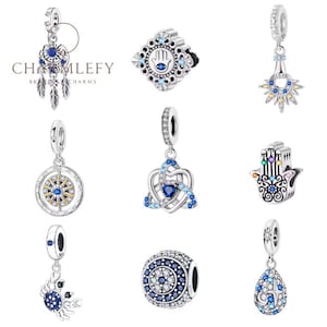 Puede incluir: Una colección de abalorios de plata con detalles de cristal azul y transparente. Los diseños incluyen un atrapasueños, una brújula, un cangrejo, un sol, una mano de Fátima y un nudo celta. Los abalorios son de la marca "CHAMLEFY CHARMS".