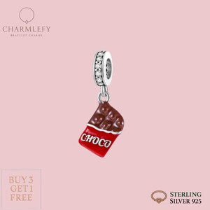 Può includere: Un charm in argento sterling con un design a barretta di cioccolato. Il charm presenta una barretta di cioccolato marrone con un involucro rosso e la parola "CHOCO" in bianco. Il charm ha un anello d'argento con pietre trasparenti.