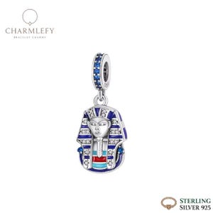 May include: A sterling silver charm with a blue and white enameled design of an Egyptian pharaoh's head. The charm has a blue beaded loop and is labeled "CHARMLEFY BRACELET CHARMS". The charm is labeled "STERLING SILVER 925".