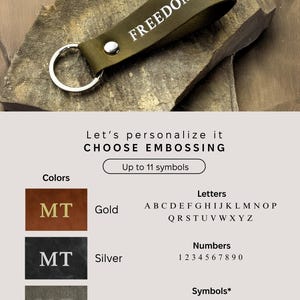May include: A green leather keychain with the word "FREEDOM" embossed in white. The keychain has a silver key ring. The image shows different options for customizing the keychain with gold, silver, or plain lettering. The text on the image reads "Let's personalize it CHOOSE EMBOSSING Up to 11 symbols Colors Letters Numbers Symbols* *Each symbol can be used only once"
