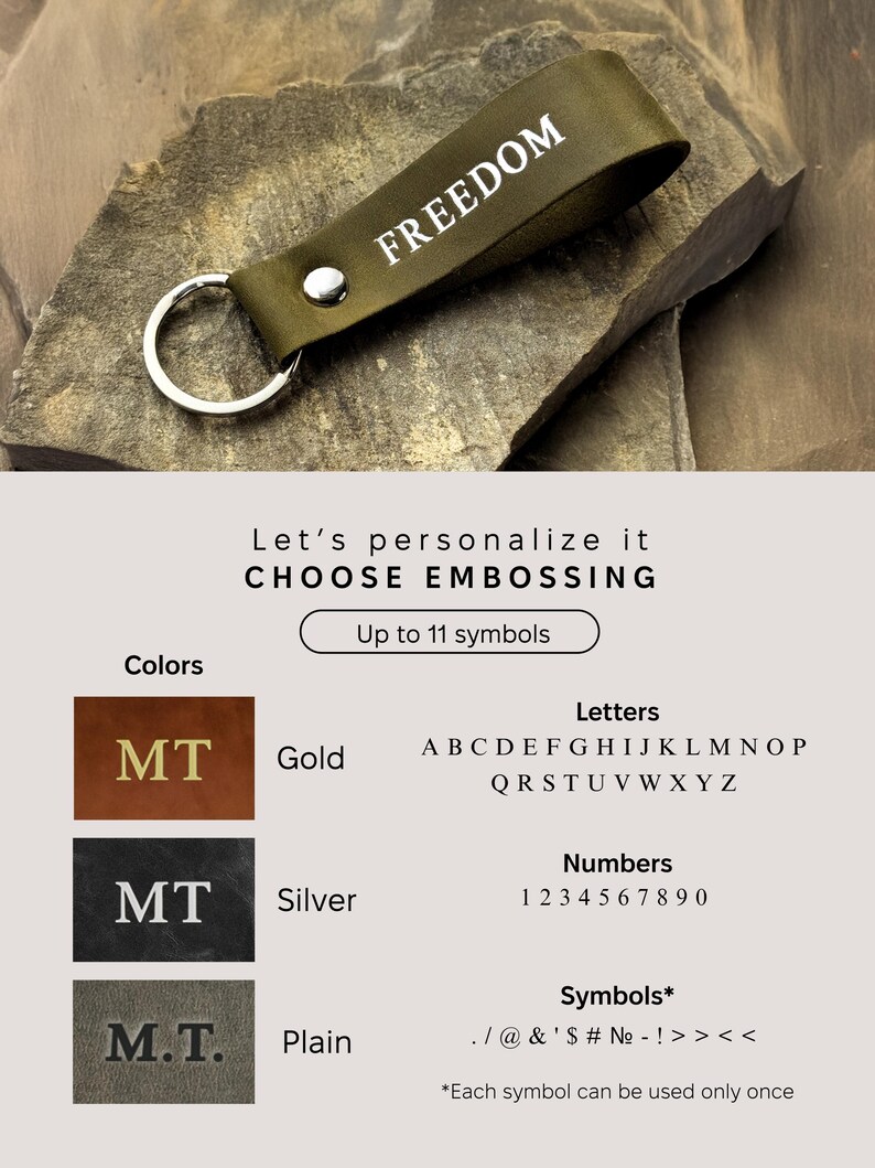 May include: A green leather keychain with the word "FREEDOM" embossed in white. The keychain has a silver key ring. The image shows different options for customizing the keychain with gold, silver, or plain lettering. The text on the image reads "Let's personalize it CHOOSE EMBOSSING Up to 11 symbols Colors Letters Numbers Symbols* *Each symbol can be used only once"