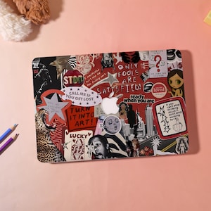 May include: A laptop cover featuring a collage of various stickers, including text such as "ONLY FOOLS ARE SATISFIED!", "TURN IT INTO ART!", "CALL ME IF YOU GET LOST", and "READY WHEN YOU ARE", alongside images of a leopard, a city skyline, and a star.
