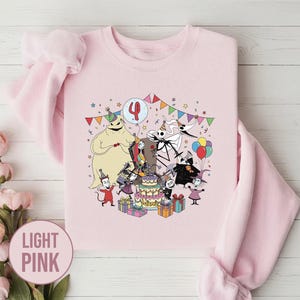 May include: Light pink sweatshirt featuring a colorful graphic of characters from The Nightmare Before Christmas celebrating a birthday. The number 4 is on a balloon. The word "Name" is on the cake. The sweatshirt is surrounded by colorful confetti and presents.