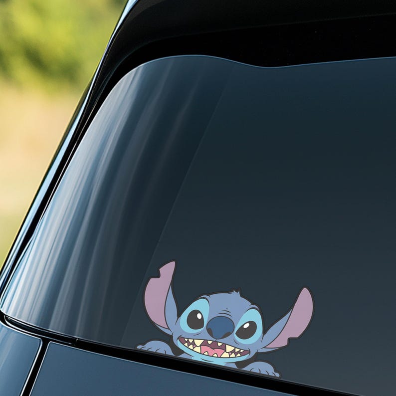 May include: A blue and purple vinyl decal of the character Stitch from the Disney movie Lilo & Stitch. The decal is applied to a car window, with Stitch peeking out from the bottom. The decal has a cartoon style.