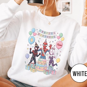 May include: White sweatshirt featuring a colorful birthday scene with Spider-Man characters. The design includes a cake, balloons, and the text "Happy Birthday." A large number 4 balloon is also present.