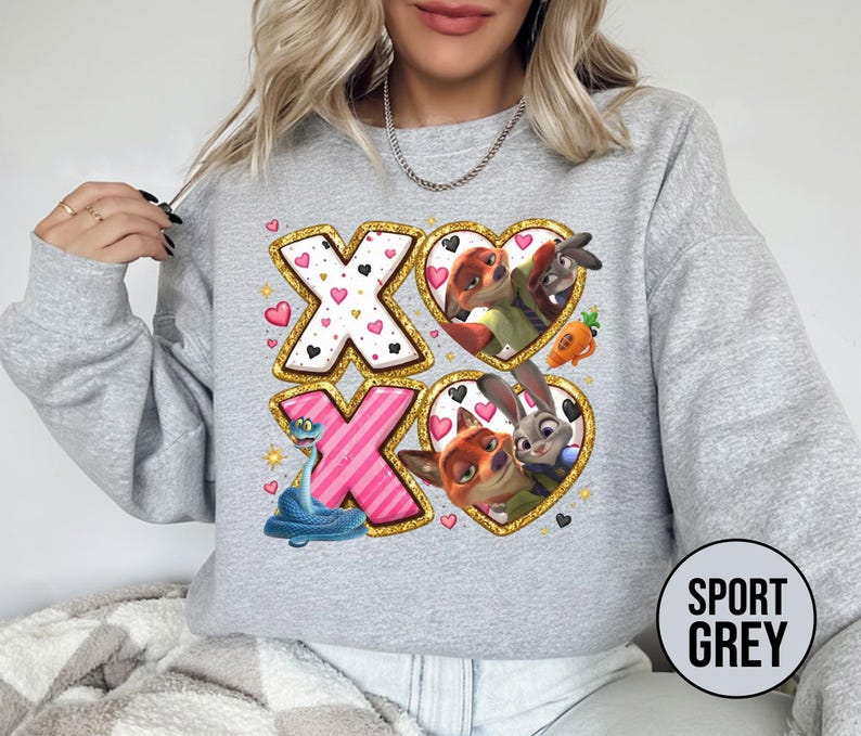 May include: Sport grey sweatshirt featuring a colorful graphic design. The design includes the letters "XO" with heart and character illustrations. The sweatshirt has a crew neck and long sleeves. The text "SPORT GREY" is printed on a circular label.