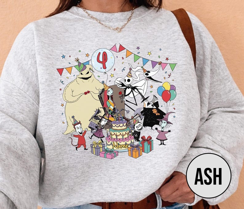 May include: A light gray sweatshirt featuring a colorful graphic of characters from The Nightmare Before Christmas celebrating a birthday. The design includes a cake, balloons, and the number 4. The characters are surrounded by colorful party decorations.