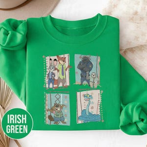 K&ouml;nnte beinhalten: Irisch gr&uuml;nes Sweatshirt mit vier gerahmten Bildern von Zootopia-Charakteren. Die Bilder zeigen Judy Hopps, Nick Wilde, Chief Bogo, Flash und andere. Das Sweatshirt hat die Worte "Irish Green" in einem gr&uuml;nen Kreis.