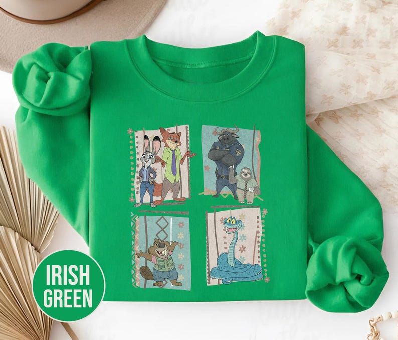 K&ouml;nnte beinhalten: Irisch gr&uuml;nes Sweatshirt mit vier gerahmten Bildern von Zootopia-Charakteren. Die Bilder zeigen Judy Hopps, Nick Wilde, Chief Bogo, Flash und andere. Das Sweatshirt hat die Worte "Irish Green" in einem gr&uuml;nen Kreis.