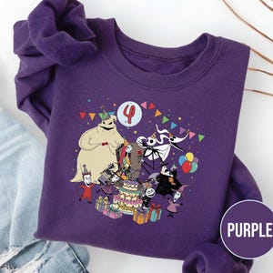 May include: Purple sweatshirt featuring a colorful graphic of characters from The Nightmare Before Christmas celebrating a birthday. The design includes a birthday cake, presents, and the number 4. The word "PURPLE" is in a circle on the bottom right.