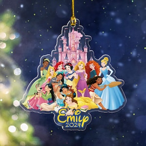 May include: A clear acrylic ornament featuring a group of cartoon princesses in colorful gowns, with a pink castle in the background. The ornament has a gold string for hanging and includes the name "Emily" and the year "2024".