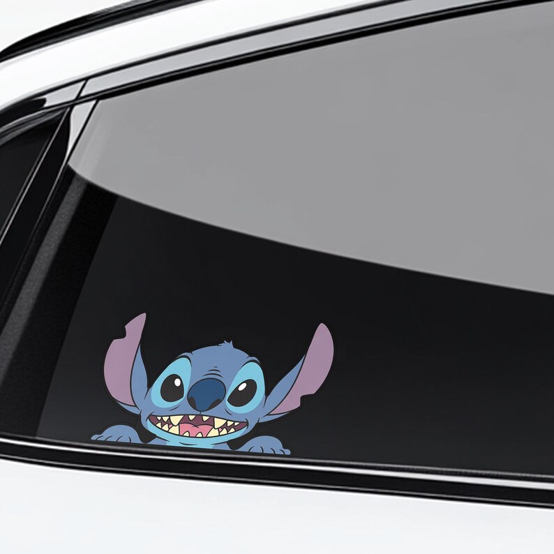 May include: A blue and purple cartoon character sticker, featuring large ears and a wide grin, is applied to a car window. The sticker is a playful design, likely for a vehicle, and adds a touch of personality.