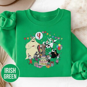 May include: Irish green sweatshirt featuring a colorful graphic of characters from a popular animated movie celebrating a birthday. The design includes a cake, presents, balloons, and the number 4.