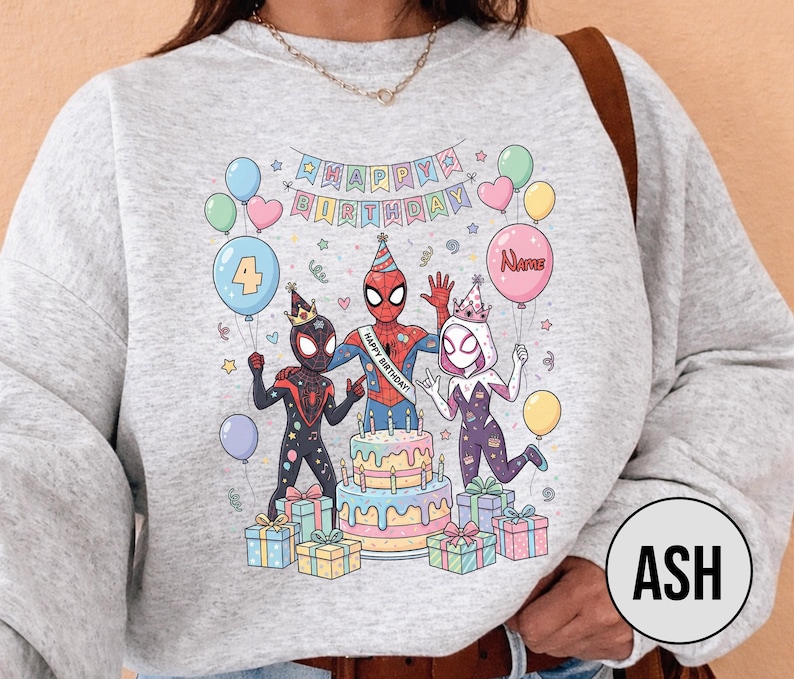 May include: A light gray sweatshirt featuring a colorful birthday design with Spider-Man characters, balloons, a cake, and wrapped gifts. The design includes the text "Happy Birthday" and a balloon with the word "Name".