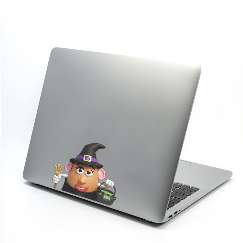 May include: A silver laptop with a colorful sticker of a potato character dressed as a witch. The character is wearing a black witch hat with a purple band and a gold buckle. It holds a trident and a cauldron.
