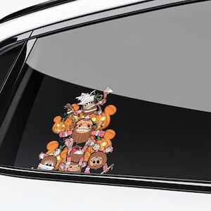 May include: A colorful Halloween-themed car decal featuring a stack of cartoon monsters and pumpkins. The monsters have various expressions and are wrapped in bandages. The pumpkins are orange with carved faces. The decal is displayed on a car window.