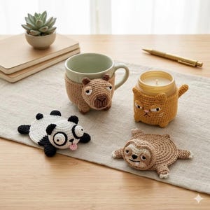 May include: A collection of handmade crochet items, including a mug cozy shaped like a capybara, a candle holder shaped like an angry cat, and animal-shaped coasters: a panda and a sloth. The items are in shades of brown, white, black, and yellow.