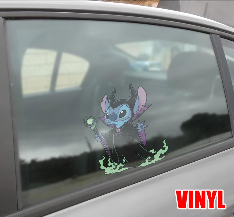 May include: A vinyl car window decal featuring a cartoon character, Stitch, dressed as Maleficent. The blue and purple character holds a staff and is surrounded by green flames. The word "VINYL" is printed in red.