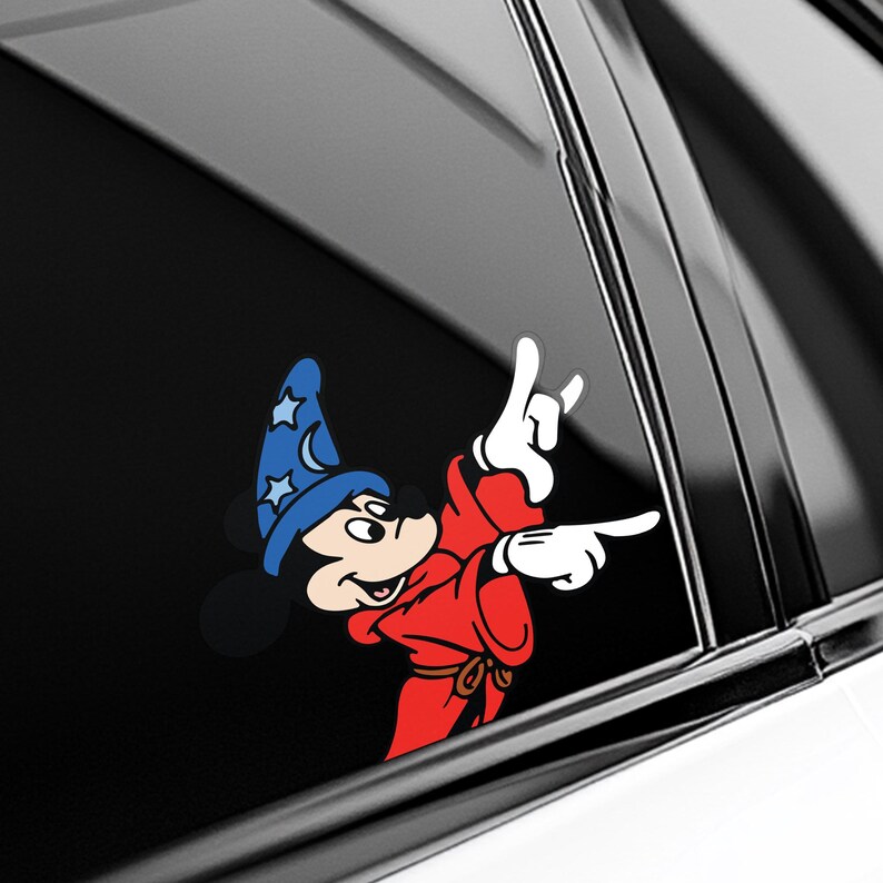 May include: A colorful vinyl decal featuring a cartoon mouse in a red robe and a blue wizard hat with stars. The mouse is making a hand gesture with its white gloved hands. The decal is designed to be applied to a car window.