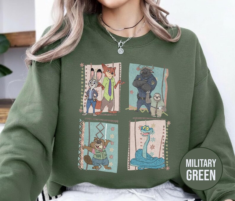 K&ouml;nnte beinhalten: Milit&auml;rgr&uuml;nes Sweatshirt mit einem Cartoon-Motiv von Charakteren aus einem Animationsfilm. Das Design zeigt ein Kaninchen, einen Fuchs, einen B&uuml;ffel, ein Faultier, einen Biber und eine Schlange. Das Sweatshirt hat einen Rundhalsausschnitt.