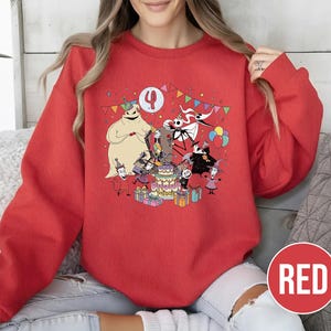 May include: Red sweatshirt featuring a colorful graphic of characters from The Nightmare Before Christmas celebrating a birthday. The design includes Jack Skellington, Sally, and Oogie Boogie around a cake, with the number 4. The word "RED" is in a red circle.