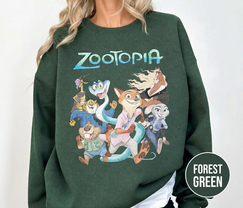 以下が含まれることがあります： アニメ映画のキャラクターのカラフルなグラフィックと「Zootopia」の文字がプリントされたフォレストグリーンのスウェットシャツ。スウェットシャツは無地のフォレストグリーンで、長袖です。