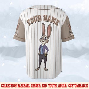 May include: White baseball jersey with brown pinstripes and sleeves. Features a cartoon rabbit character on the back, with the text "YOUR NAME" above. The jersey has a button-up front and a collar. The text "COLLECTION BASEBALL JERSEY/ KID, YOUTH, ADULT/ CUSTOMIZABLE" is at the bottom.