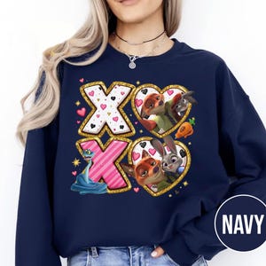 May include: Navy blue sweatshirt featuring a design with the letters "XO" in gold glitter. The "X"s are decorated with hearts and a blue snake. The "O"s are heart-shaped with cartoon characters. The word "NAVY" is in a circle.