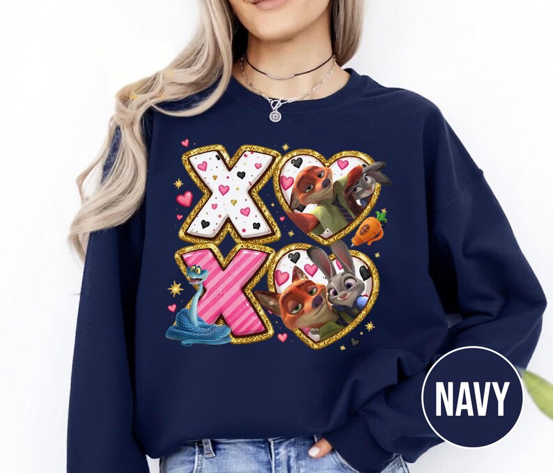 May include: Navy blue sweatshirt featuring a design with the letters "XO" in gold glitter. The "X"s are decorated with hearts and a blue snake. The "O"s are heart-shaped with cartoon characters. The word "NAVY" is in a circle.