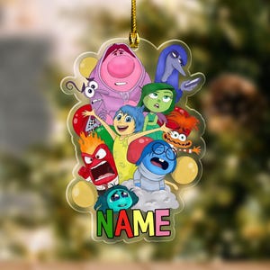 May include: A clear, cloud-shaped ornament featuring characters from the animated movie "Inside Out." The ornament has a gold string for hanging. The characters include Joy, Sadness, Anger, Fear, Disgust, and Bing Bong. The word "NAME" is at the bottom.