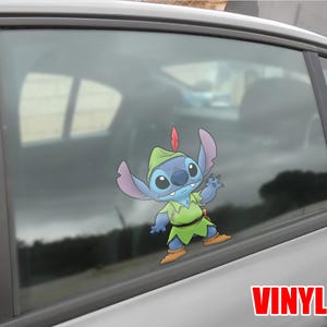 May include: A blue and green vinyl decal of the character Stitch dressed as Peter Pan, with a red feather in his hat. The decal is applied to a car window. The word "VINYL" is printed in red.