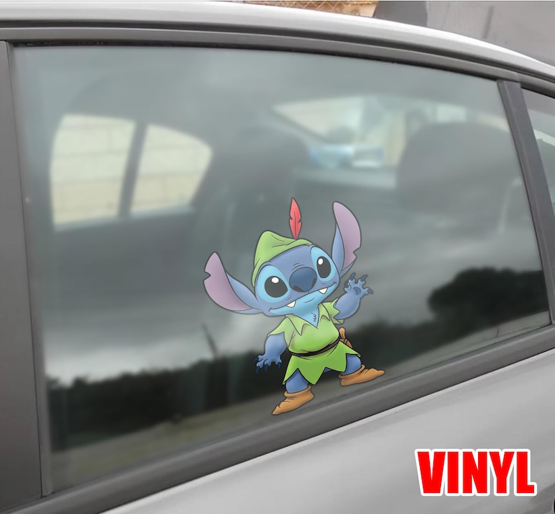 May include: A blue and green vinyl decal of the character Stitch dressed as Peter Pan, with a red feather in his hat. The decal is applied to a car window. The word "VINYL" is printed in red.