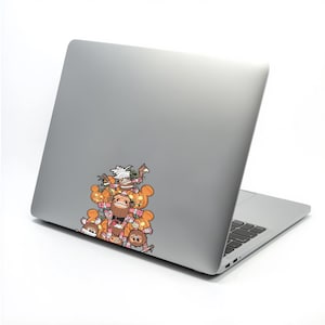 May include: A silver laptop with a colorful sticker featuring cartoon characters and orange pumpkins. The sticker is on the upper left corner of the laptop. The characters have various expressions and are in a pile.
