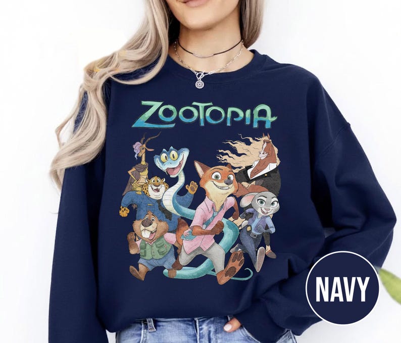 以下が含まれることがあります： ターコイズ色の「Zootopia」の文字と、アニメ映画のキャラクターのカラフルなグラフィックが特徴のネイビーブルーのスウェットシャツ。デザインにはキツネ、ウサギ、その他の動物のキャラクターが含まれています。スウェットシャツはクルーネックと長袖です。