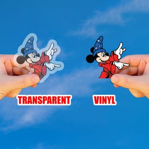 May include: Two stickers featuring Mickey Mouse in a sorcerer's outfit, one transparent and one vinyl. Mickey is wearing a blue hat with stars and a red robe, pointing with his right hand. The word "TRANSPARENT" and "VINYL" are displayed.
