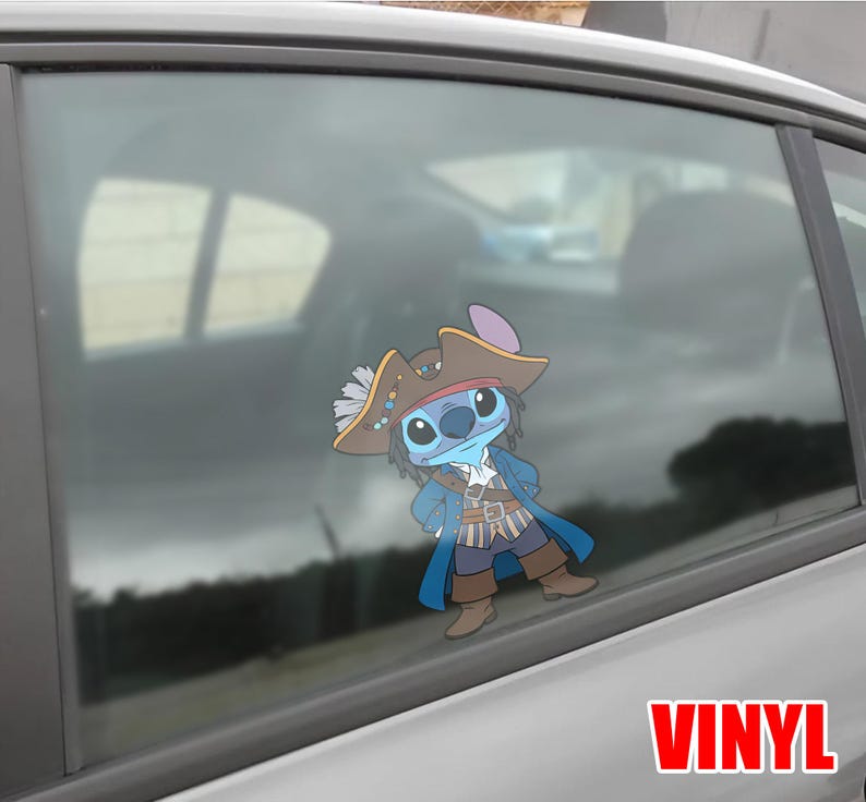 May include: A blue cartoon character wearing a pirate hat and costume, with the word "VINYL" in red block letters. The character is affixed to a car window, with a blurred background visible through the glass.