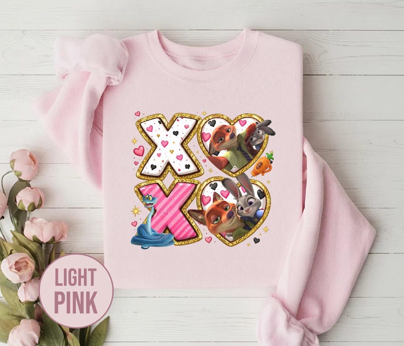 May include: Light pink sweatshirt with a graphic design featuring the characters from Zootopia. The design includes the letters "XO" with heart and character illustrations. The text "LIGHT PINK" is in a pink circle.