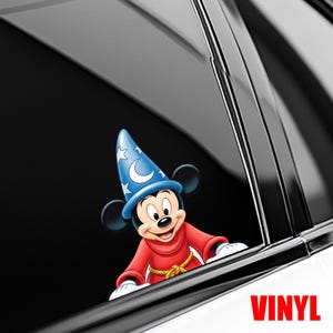 May include: A colorful vinyl decal featuring Mickey Mouse in a sorcerer's outfit. Mickey is wearing a blue hat with stars and a crescent moon, a red robe, and a gold rope belt. The word "VINYL" is printed in red.