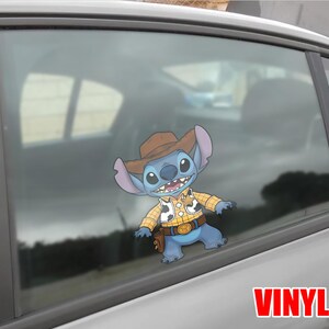 May include: A blue cartoon character wearing a cowboy hat, yellow plaid shirt, and a belt with a gold buckle. The character is a vinyl sticker on a car window. The word "VINYL" is printed in red at the bottom.