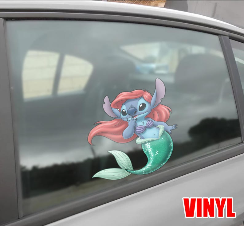 May include: A blue and pink cartoon character with a mermaid tail, resembling a Disney character, is featured on a car window. The character has pink hair, a blue body, and a green tail. The word "VINYL" is printed in red.