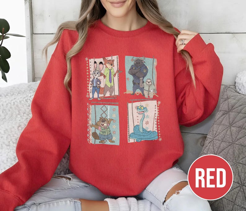 K&ouml;nnte beinhalten: Ein rotes Sweatshirt mit vier illustrierten Panels von Zeichentrickfiguren. Die Panels zeigen ein Kaninchen, einen Fuchs, einen B&auml;ren, ein Faultier, einen Biber und eine Schlange. Das Wort "RED" befindet sich in einem roten Kreis unten rechts.