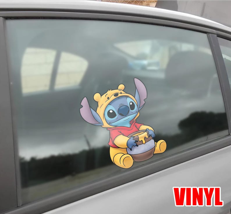 May include: A vinyl car decal featuring the character Stitch from Lilo & Stitch, dressed in a Winnie the Pooh costume, holding a honey pot. The decal is in full color and is applied to a car window.