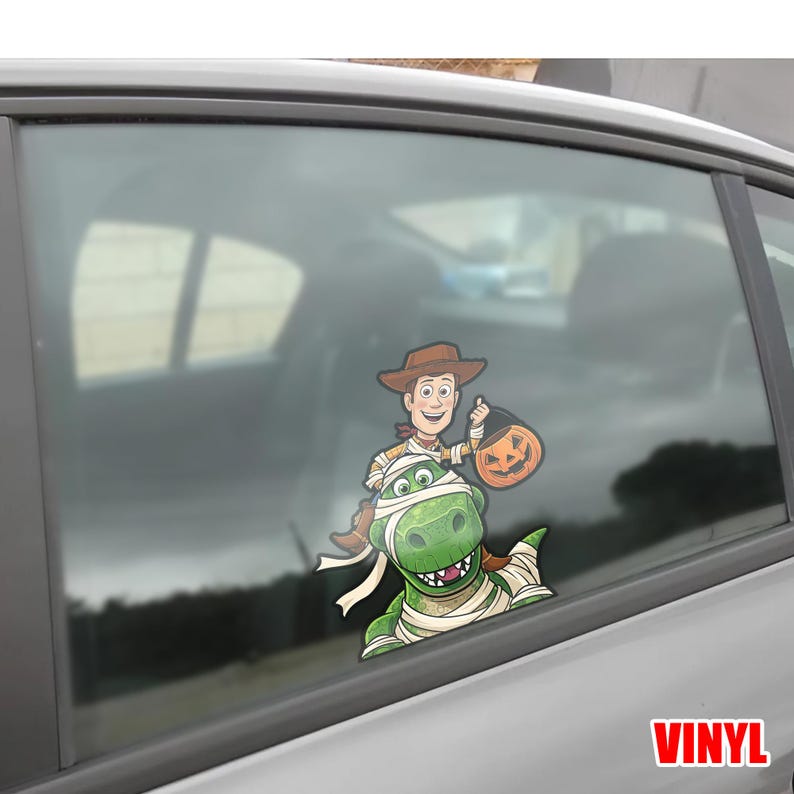May include: A colorful vinyl decal featuring Woody from Toy Story holding a jack-o'-lantern treat bag, riding on a green dinosaur wrapped in bandages. The word "VINYL" is in the bottom right corner.