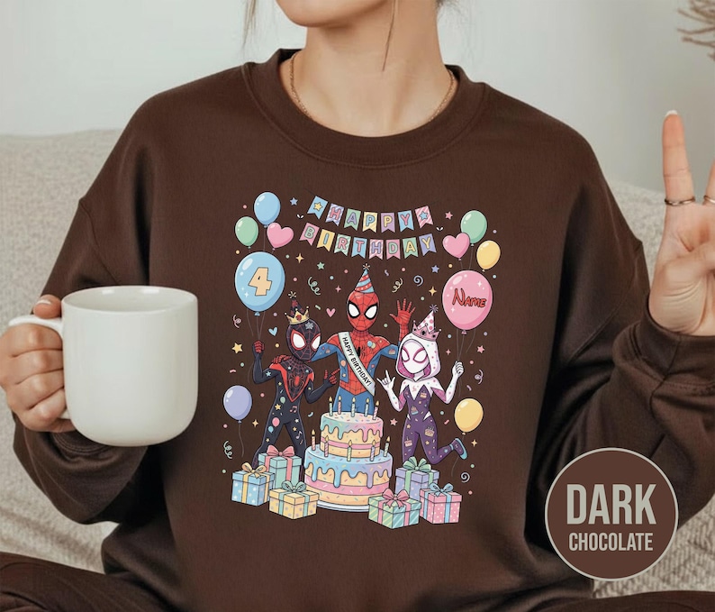 May include: Dark chocolate brown sweatshirt featuring a colorful graphic of Spider-Man characters celebrating a birthday. The design includes a cake, balloons, and the words "Happy Birthday". The number "4" is on a balloon.