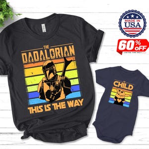 May include: Black t-shirt with "THE DADALORIAN" and "THIS IS THE WAY" text, featuring a Mandalorian graphic. A navy blue onesie with "CHILD" text and a Grogu graphic is also shown. Made in USA.