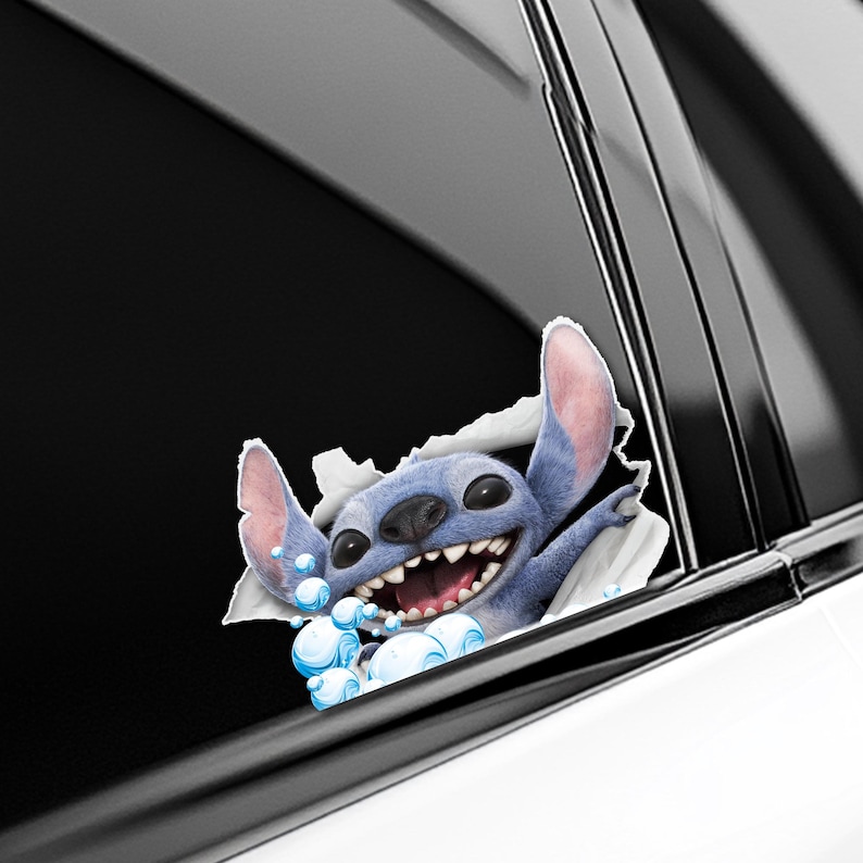 Puede incluir: Un personaje de dibujos animados azul, Stitch, irrumpe a trav&eacute;s de una superficie blanca, con una gran sonrisa y burbujas. El personaje tiene orejas grandes y una expresi&oacute;n amigable. La imagen es una calcoman&iacute;a para coche.
