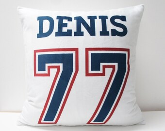 May include: White pillow with the name "DENIS" and the number "77" in blue and red lettering.